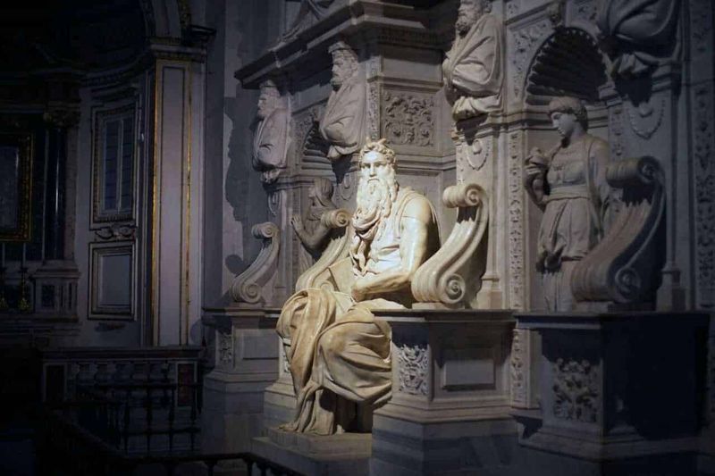 Cosa vedere a Roma gratuitamente 3 Scultura barocca di un saggio con barba lunga all’interno di un museo storico, decorazioni artistiche e dettagli in marmo bianco.