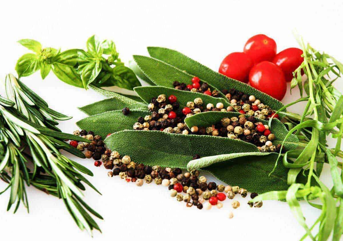 Dei vari tipi di erbe aromatiche e spezie come basilico, rosmarino, salvia, pepe e timo disposte su uno sfondo bianco. Perfette per cucina, come decorazioni o utilizzo in ricette mediterranee.