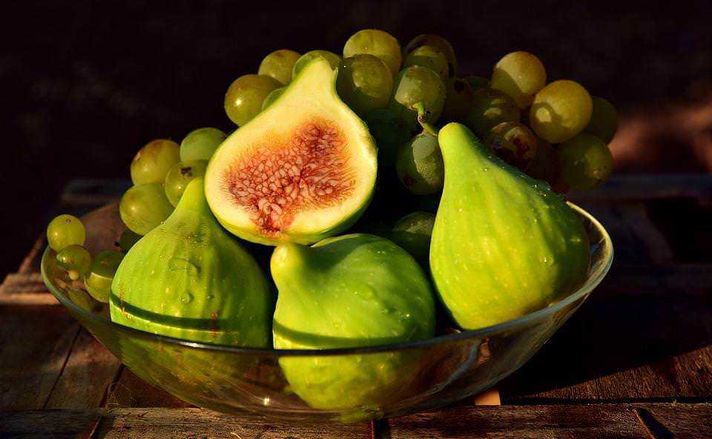 Frutti esotici top 23 dal mondo sulla tavola 8 Uva e fichi freschi in una ciotola, succosi e apprezzati come frutti estivi naturali, ideali per uno spuntino salutare e ricco di fibre, perfetti per arricchire insalate e dessert.