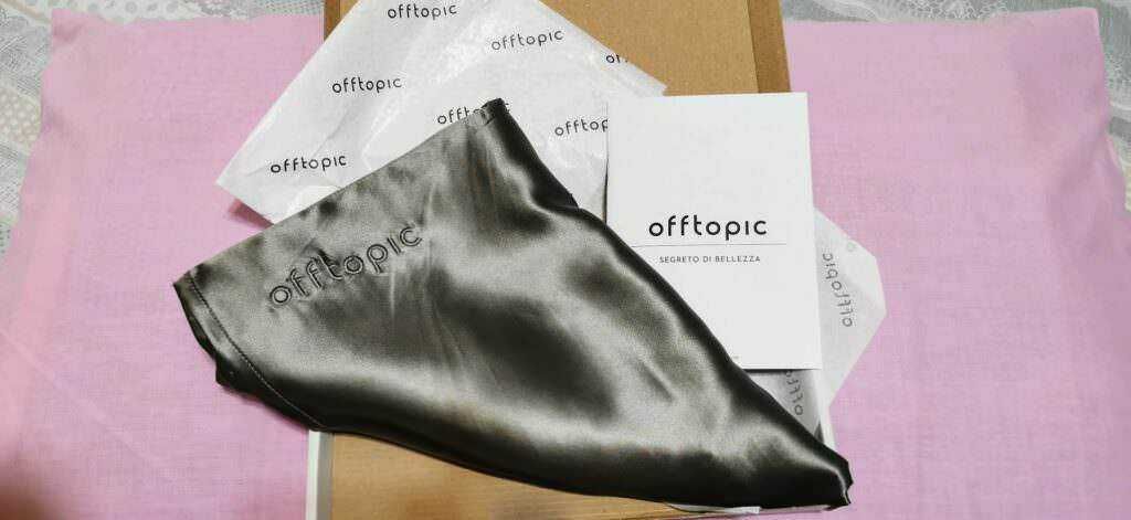 Candela di bellezza in satin nero con packaging offtopic, saponi e accessori per la cura della pelle, presentati su sfondo rosa e carta kraft, ideali per prodotti di cosmetica e beauty routine.