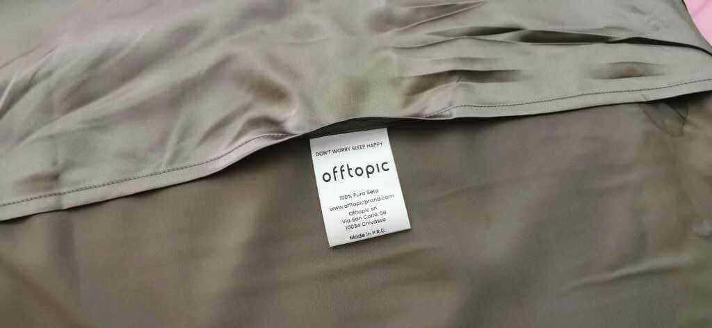 Federe letto in seta beige con etichetta visibile, tessuto di alta qualità e comfort elegante. Perfetto per un sonno rilassante e stile sofisticato.