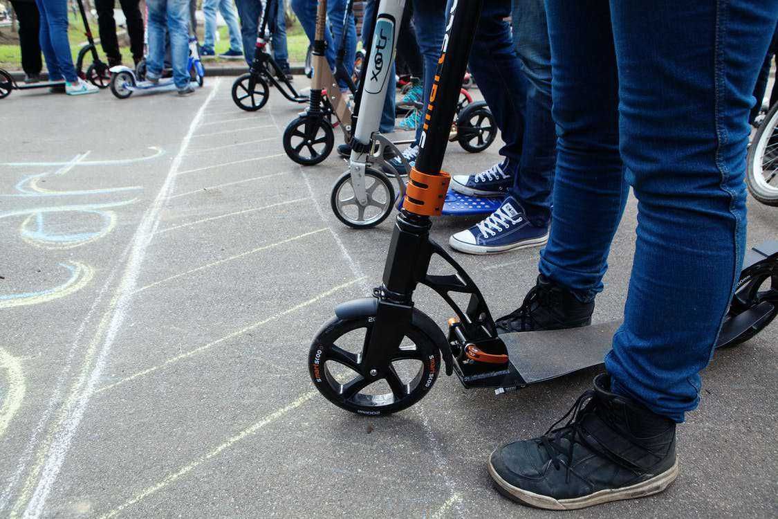 Scooter elettrica in fila, persone in attesa di utilizzo, evidenza di mobilità urbana sostenibile e trasporto ecologico, protagonisti di un evento pubblico all'aperto.