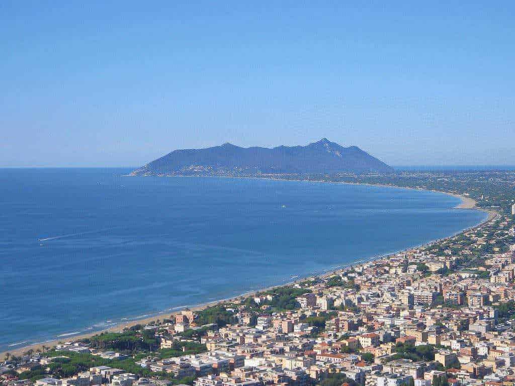 Appunti Sul Blog - Panorama della città sul mare con montagna sullo sfondo, vista aerea di un'area urbana costiera, spiaggia lunga e acque cristalline, ideale per contenuti di viaggio e turismo in Italia.