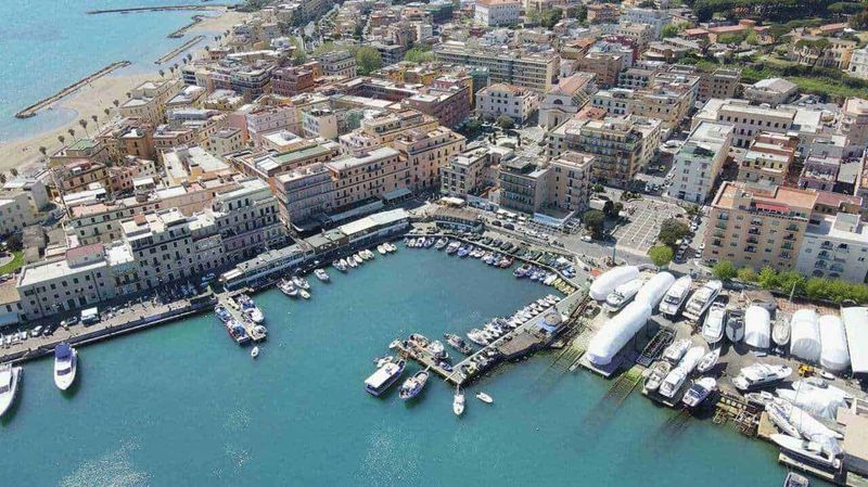 7 borghi tra Riviera di Ulisse, Monti Lepini e spiagge 3 Vita di mare e città costiera, porto turistico con yacht e imbarcazioni, veduta aerea del centro storico di una località marina in Italia, con edifici colorati e mare cristallino.