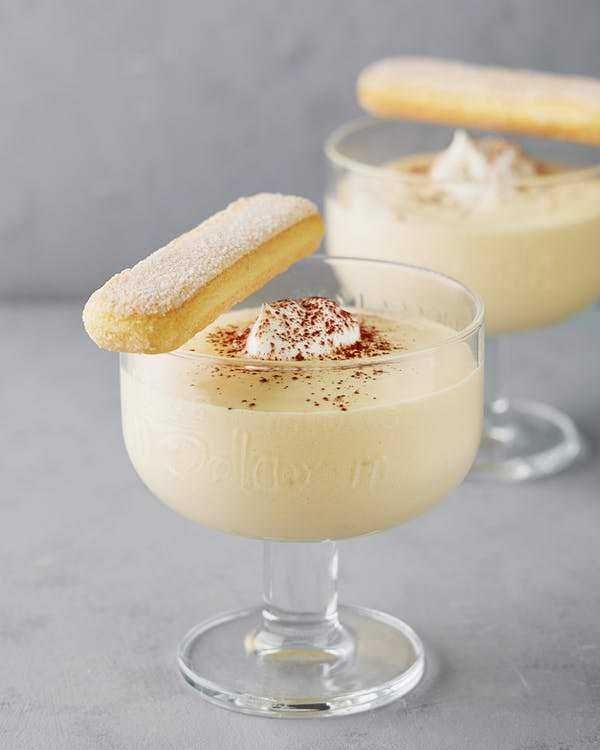 Dessert estivo fresco e leggero: Crema di mascarpone e panna con biscotto alla vaniglia, dolce al cucchiaio, perfetto come dessert, decorato con cacao amaro, in bicchiere elegante.