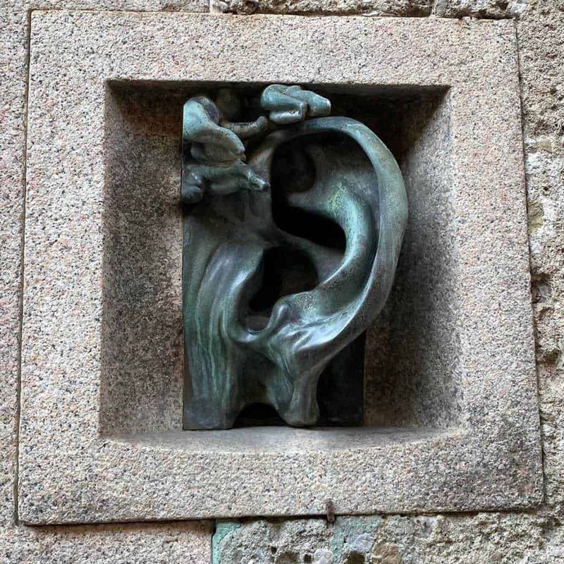 Milano, tra fenicotteri rosa e 4 luoghi segreti da scoprire inconsueti 4 Sculptura moderna in pietra raffigurante un orecchio e un volto stilizzato, decorazione artistica su parete di edificio.