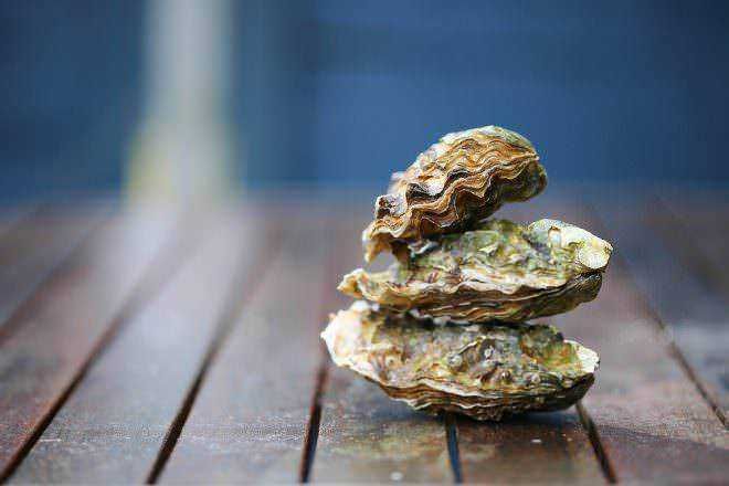 Conchiglie ostrica fresche e aperte su superficie in legno, dal mare alle ricette di cucina, simbolo di mare e mareggiata, ideale per ristorante di pesce e gastronomia di mare.