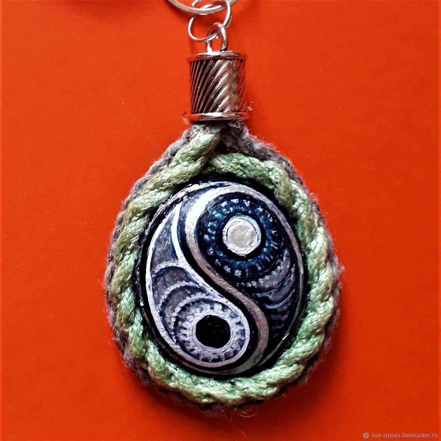 Pendente con simbolo yin-yang e piuma, realizzato con tessuto e metallo, design artigianale, gioielli etnici, accessorio boho chic, decorazione originale, complementi di stile, artigianato italiano, regalo originale, decorazione spirituale.