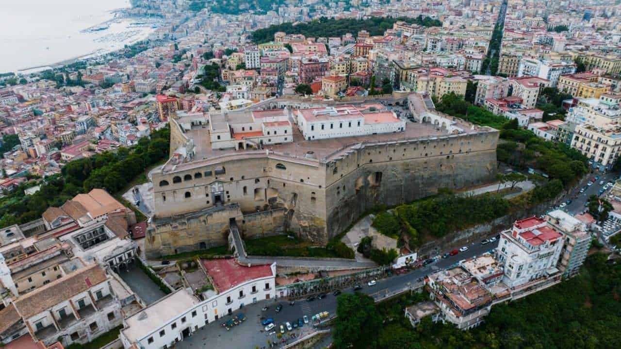 Rocca di Messina vista dall'alto, fortificazione storica nel centro della città, Sicilia, con strade e edifici colorati circostanti.