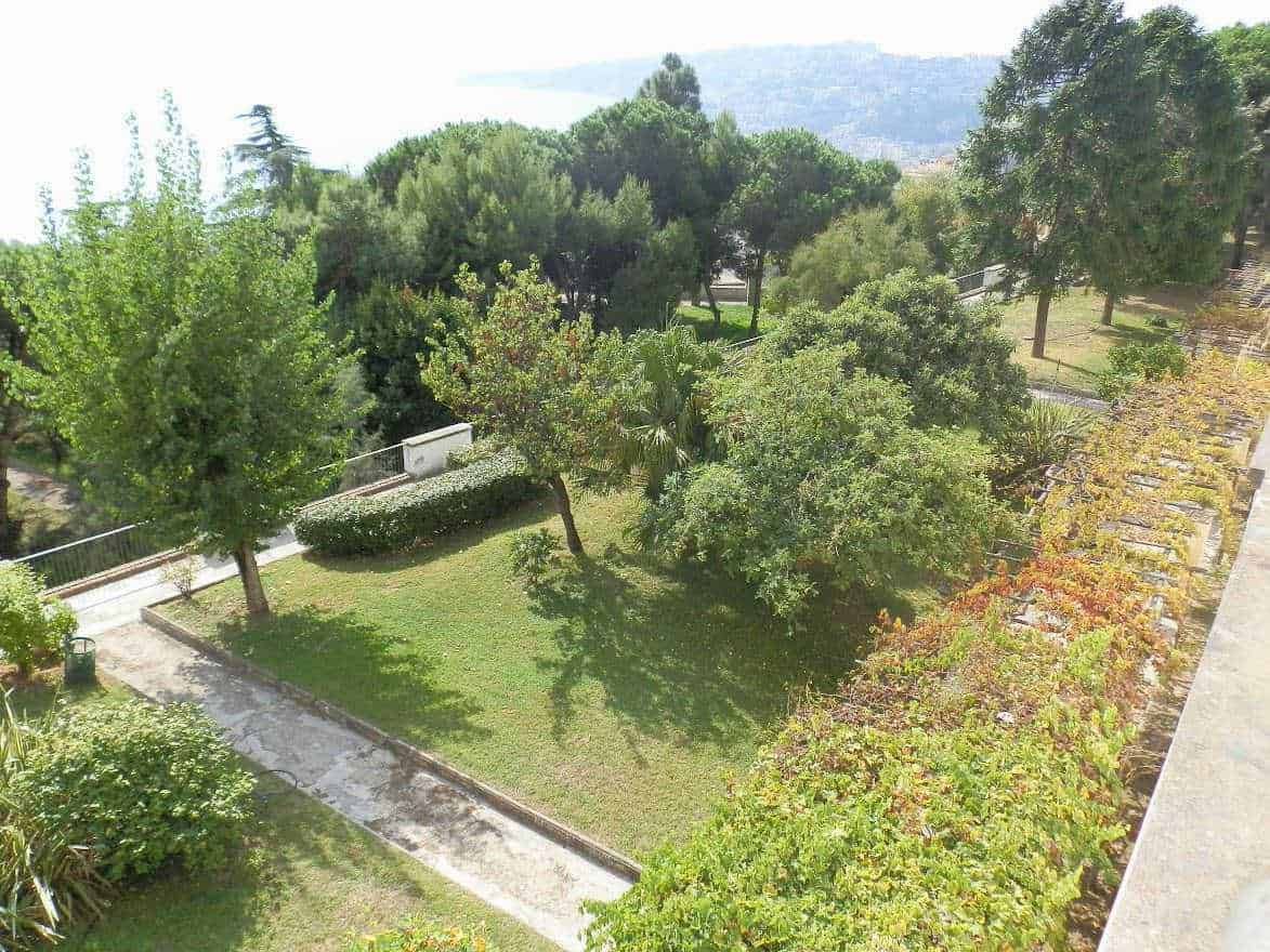 Giardino pubblico con alberi e piante verdi, vista dall'alto, prato ben curato, perfetto per relax e passeggiate, in un'area naturale e tranquilla.
