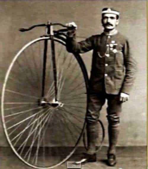 Il personaggio storico in uniforme militare con un monociclo d'epoca, posa con atteggiamento deciso. Immagine in stile vintage, simbolo di innovazione e resistenza, rappresenta un momento storico importante.