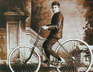Bicicletta d'epoca con bambino in posa su sfondo storico, immagine vintage alla moda, nostalgia anni passati, passatempo all'aperto, ritratto nostalgico in stile vintage.