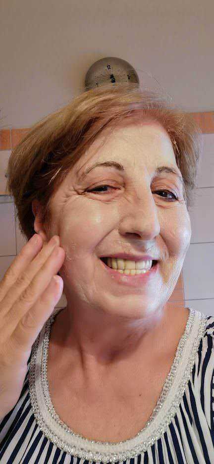 Smiley donna anziana che si tocca il viso con una mano, immagini di benessere e cura della pelle.