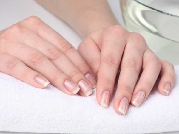 Come cresce un'unghia: Primo piano su mani che ricevono una manicure in un salone di bellezza, focus su cura delle unghie e trattamenti estetici, ambiente rilassante e professionale.