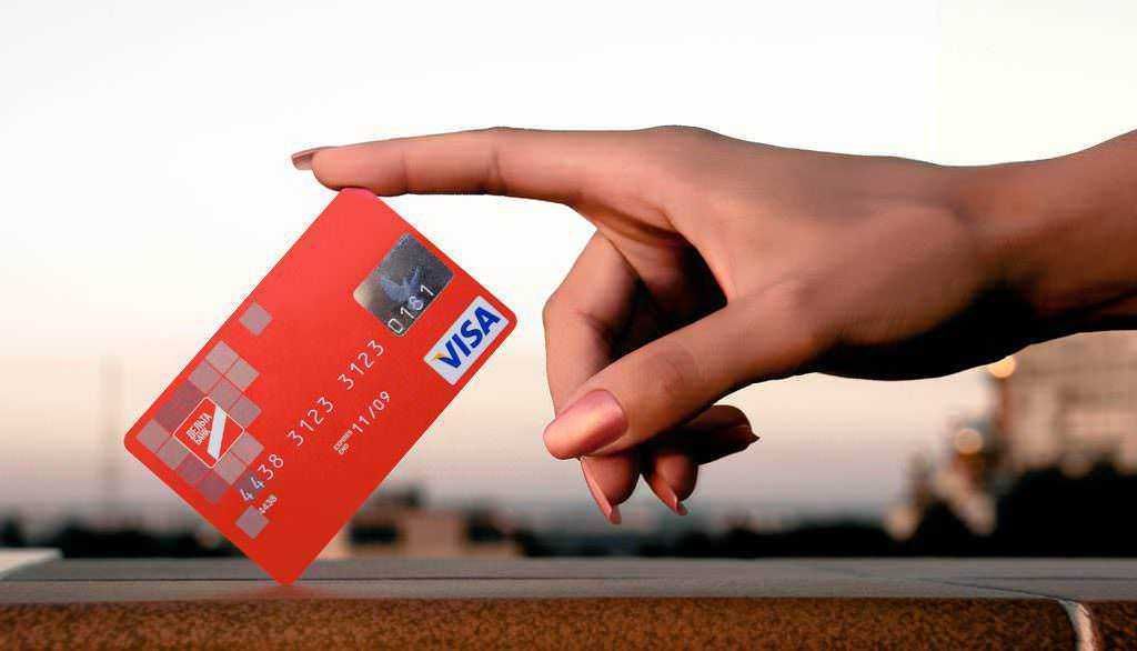 Carta di debito e credito: Carta di credito Visa tra le dita, fotografia di pagamento digitale e sicurezza finanziaria.