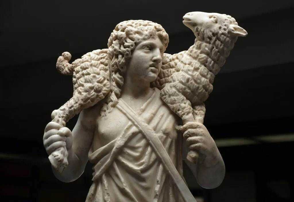 Dell'antica scultura in marmo raffigurante un giovane eroe mitologico con maschera leonina, tenue espressione e dettagli curati, simbolo della cultura e dell'arte classica italiana.