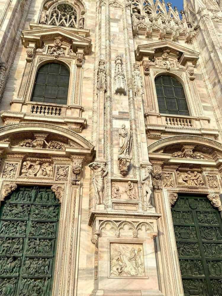Antica facciata della Cattedrale di Milano con dettagli delle sculture in marmo e le grandi vetrate, esempio di architettura rinascimentale, patrimonio storico e artistico della città.