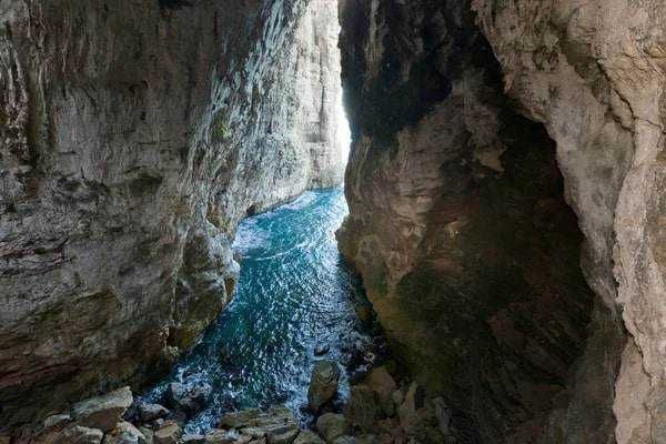 Dolina tra scoglietes e acqua cristallina in natura, canyon roccioso con acque turchesi, pareti di roccia alte e strette, paesaggio naturale spettacolare, formazione rocciosa unica, escursioni e avventure all'aperto, destino ideale per amanti della natura.