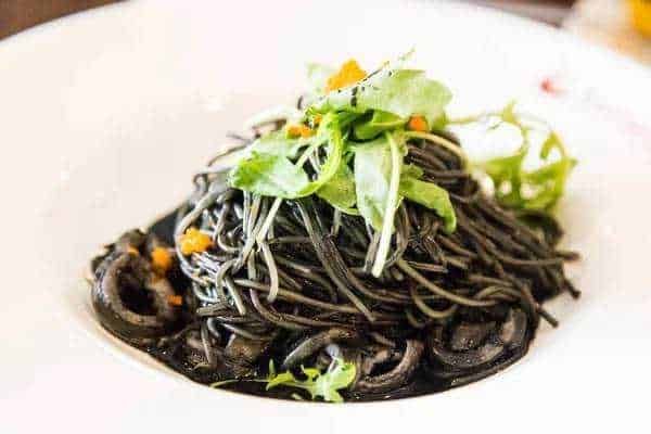 Spaghetti alla Carbonara con uova, pancetta e formaggio, serviti con una generosa spolverata di pepe nero e pepe nero macinato fresco, un piatto classico della cucina italiana.