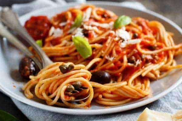 Pasta spaghetto con sugo di pomodoro, olive nere e basilico fresca, piatto tradizionale italiano, cibo italiano autentico, ricetta italiana classica, spaghetti al pomodoro, cucina italiana genuina.