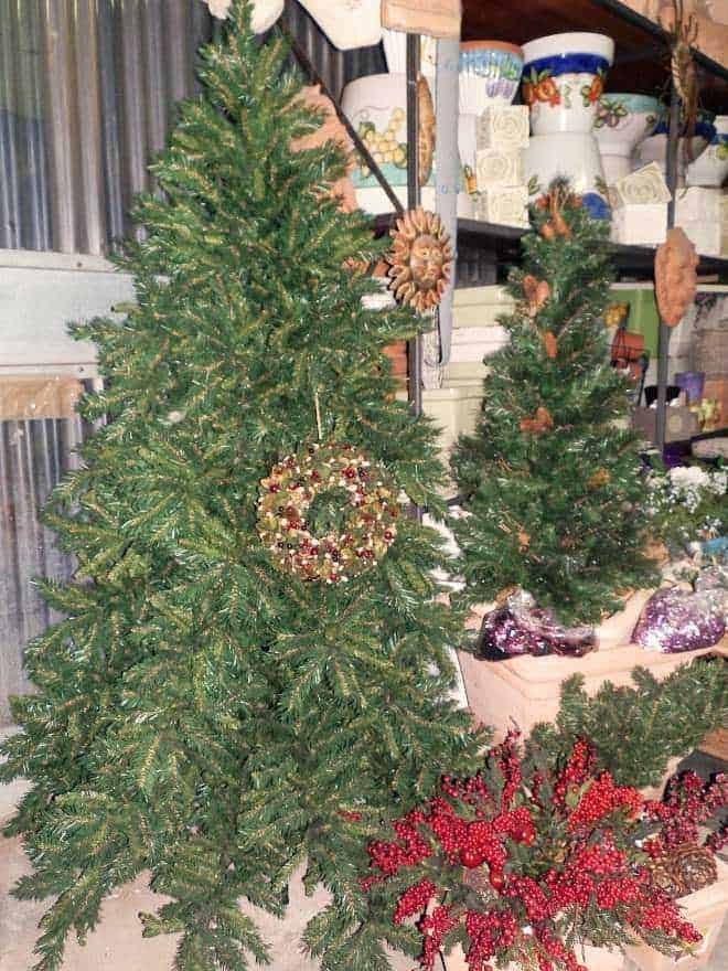 Naturale alberi di natale decorati con bacche rosse e ornamenti natalizi, pronti per le festività, in un laboratorio di decorazioni natalizie.
