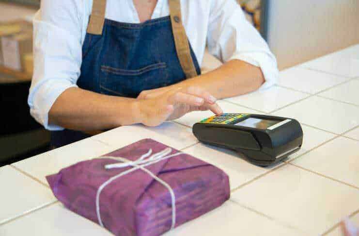 Pagamento contactless con POS in negozio, donna che effettua pagamento senza contatto.Pagamento digitale, smart payment, commercio elettronico, tecnologia di pagamento, negozio modernizzato.
