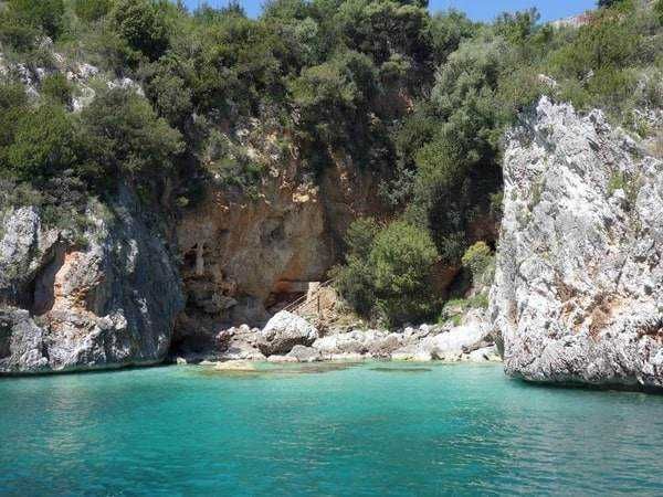 Spiaggetta nascosta tra scogli e vegetazione verde, acque cristalline e natura incontaminata, ideale per relax e avventura in sicurezza.