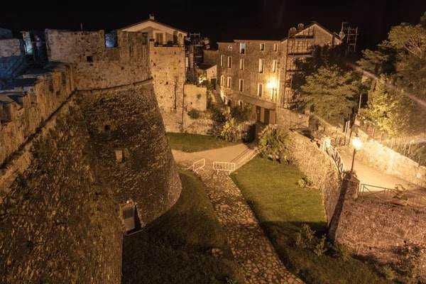 Antico bastione medievale con mura di pietra e vista notturna sul centro storico illuminato, creando un'atmosfera suggestiva e tranquilla nel cuore di un'affascinante città storica italiana.