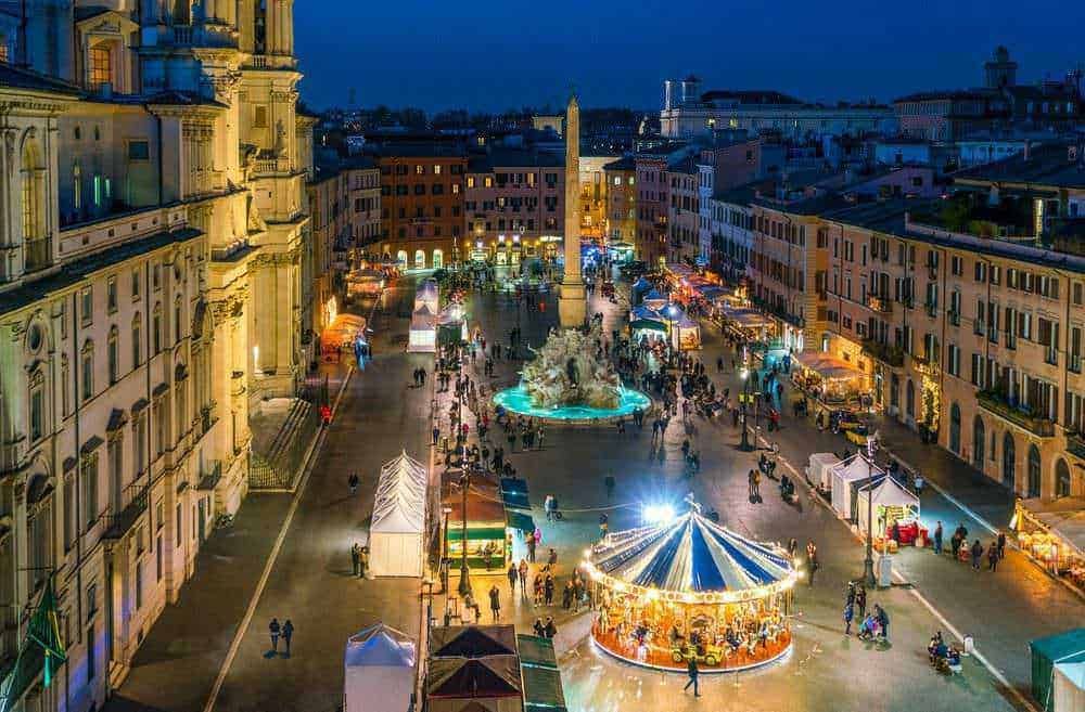 Vignole medievali di Lucca illuminate durante un evento all'aperto, con mercatino e luci decorative, creando un'atmosfera festiva e suggestiva nel centro storico di Lucca, Italia.