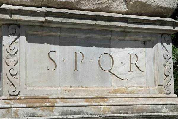 Mura storiche di Roma con camminamento e parapetto in ferro, sotto un cielo azzurro con nuvole bianche, emerge l'antica sicurezza e bellezza della città eterna.