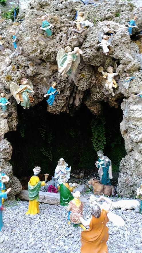Angeli e pastori in presepe natalizio all’interno di una grotta con dettagli realistici e colori vivaci, perfetto come decorazione per il periodo natalizio e rappresentazione della Natività.