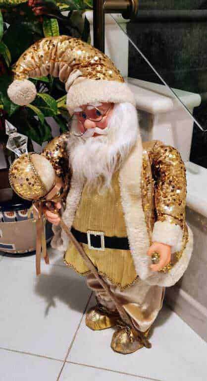 Vestito natalizio di Babbo Natale in oro e bianco con cappello glitterato, accessori festivi, ambientazione allegra, decorazioni natalizie, atmosfera di festa, decorazioni di Natale, personaggio di Babbo Natale.