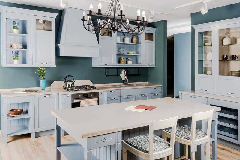 I colori più belli per la tua casa, tendenze 2023 6 Bellissima cucina moderna con mobili bianchi e pareti color teal, penombra luminosa e dettagli d'arredo eleganti, ideale per uno stile di vita funzionale e accogliente.