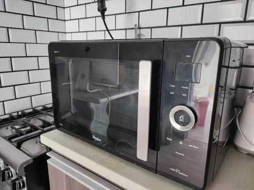 Microonde nero con display digitale e maniglia in cucina moderna.