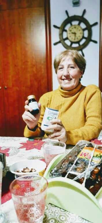 Integratore vitaminico colluttorio in bottiglia alcolica per il benessere orale, donna che lo mostra sorridendo in casa.
