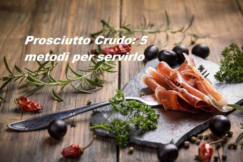 Prosciutto crudo in stile rustico con erbe aromatiche e olive nere su un tagliere di legno, perfetto per antipasti e aperitivi, un classico della cucina italiana.