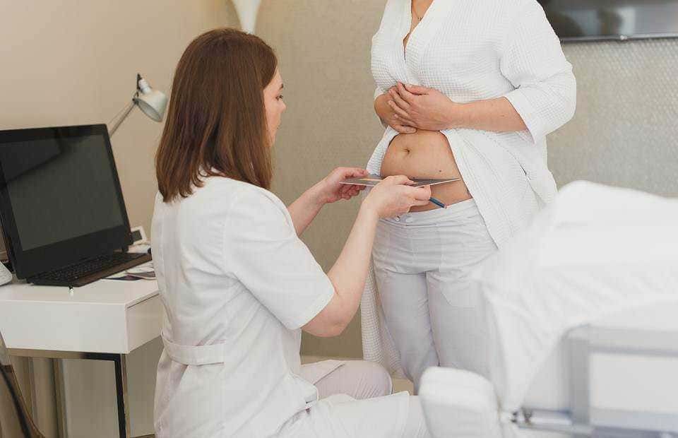 Stetoscopio in gravidanza, ginecologo che ascolta il battito fetale di una donna incinta nell'ambulatorio medico.