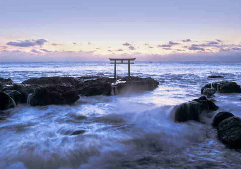Cancello Kamiiso no Torii Torre shinto su scogliata marina durante tramonto, simbolo culturale giapponese con paesaggio marino in lontananza.