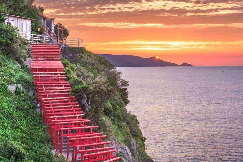 Santuario di Motonosumi Scale di scale in legno rosso sulla scogliera con vista mare al tramonto, paesaggio costiero giapponese, atmosfera serena, natura e cultura, immagini di viaggi e viaggio, natura e paesaggi, bellezza naturale dell'oceano, attrazioni turistiche, escursioni e trekking, fotografie di paesaggi e natura, emozioni di viaggio e avventura.