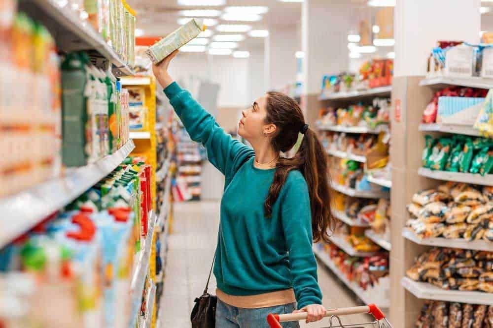 Prodotto alimentare in vendita al supermercato, donna che sceglie cibo sugli scaffali, spesa quotidiana, acquisti di generi alimentari, shopping in negozio di alimentari, shopping groceries, selezione di prodotti alimentari.