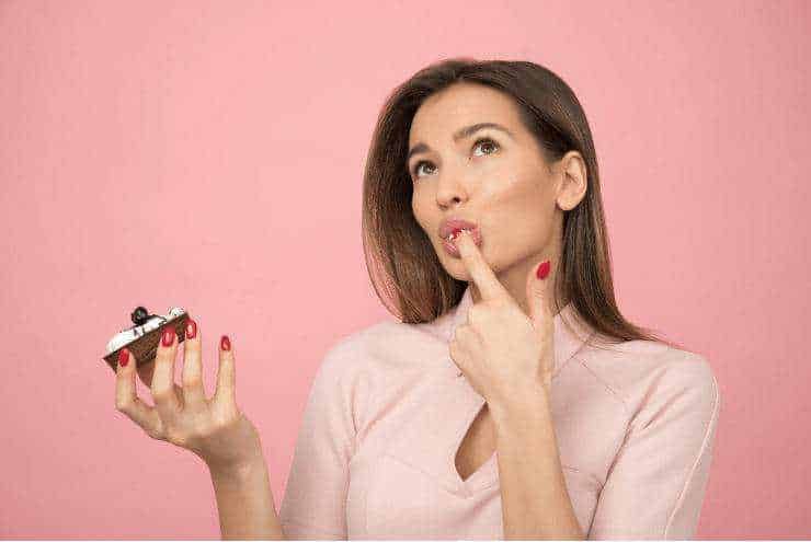 Fame emotiva: Pensatrice donna con ciglia lunghe, trucco naturale, sfondo rosa, che riflette e pensa, in uno stile fotografico editoriale, ideale per contenuti di blog, pensieri e idee creative.