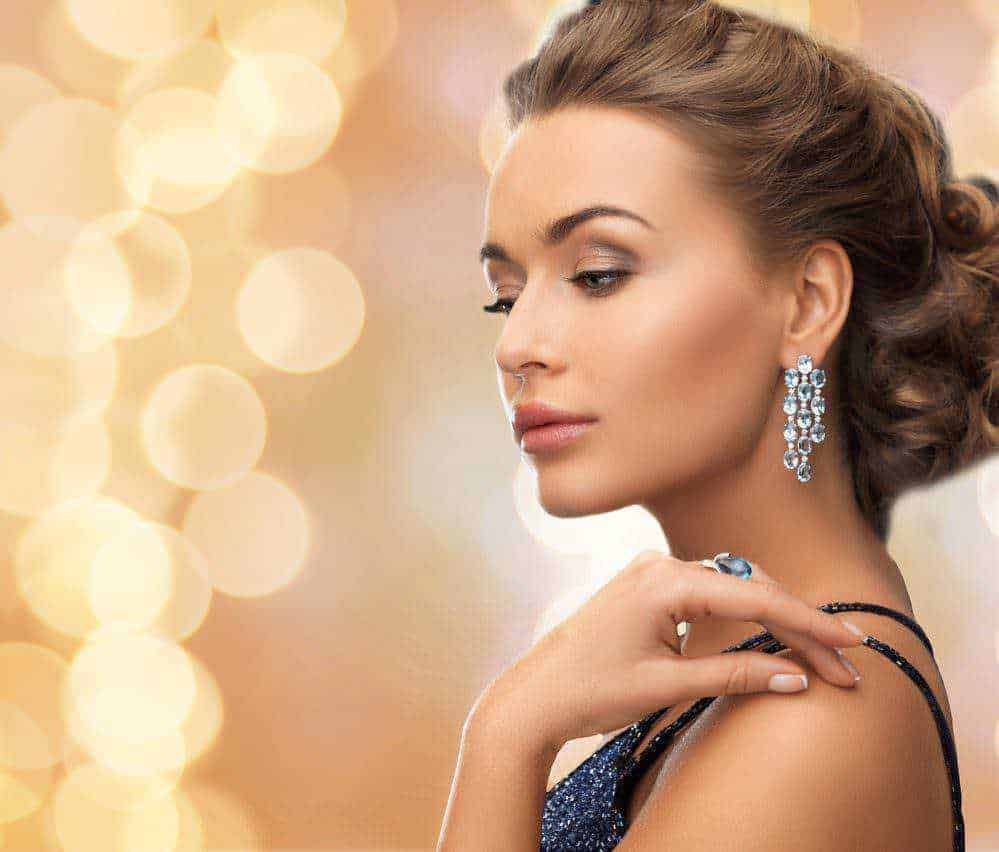 Outfit per sanremo 2023: Elegante donna con orecchini di diamanti e vestito blu scuro, foto di alta qualità, illuminata da luci calde, perfetta per blog di moda e bellezza.