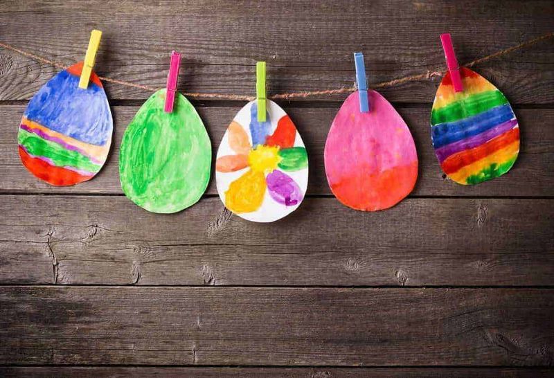 Celebrando la Pasqua 3 tradizioni secolari 4 Colorate uova di Pasqua dipinte a mano appese su una corda con mollette di legno su sfondo di legno rustico.