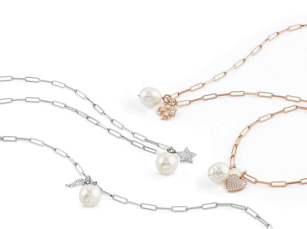 Collane con perle e charms in argento e oro rosa su sfondo bianco elegante e minimalista, perfette per accessori moda femminili raffinati e di classe.