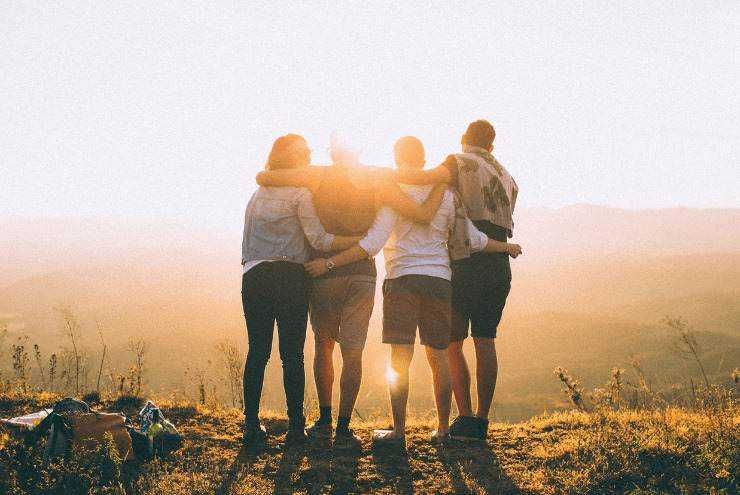 Amici che camminano insieme durante il tramonto, simbolo di amicizia e avventura all'aperto.