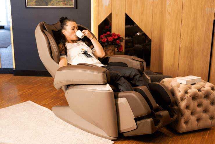 Relax donna in poltrona massaggiante che sorseggia una tazza di tè, ambiente confortevole e moderno, perfetto per il benessere e il relax totale.