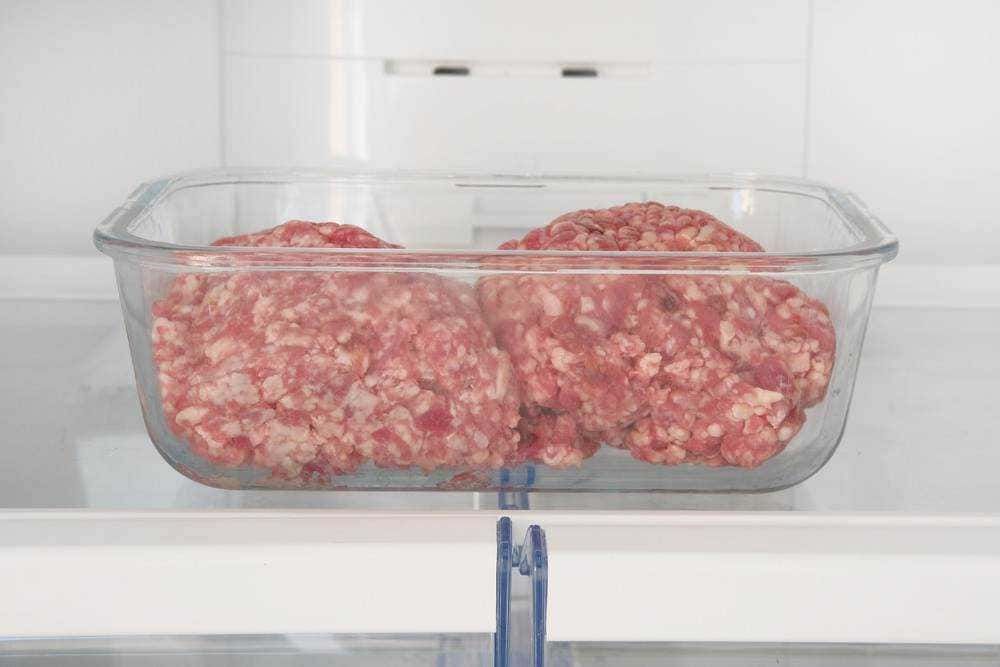 Carne macinata fresca in contenitore di vetro nel frigorifero, pronta per cucinare o conservare, ideale per ricette di carne e cucina italiana.