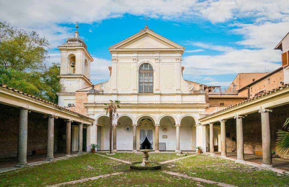 Antico cortile con chiesa barocca e portici in pietra, atmosfera storica e artistica in Italia. Edificio storico in pietra bianca con colonne e colonne in cortile, perfetto esempio di architettura religiosa e antica.