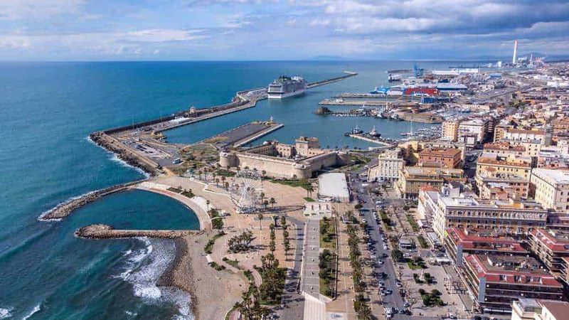 11 Borghi e luoghi da visitare nel Lazio Nord-Ovest 3 Vista panoramica del porto di Cagliari con imbarcazioni, strutture portuali e il mare durante una giornata soleggiata.