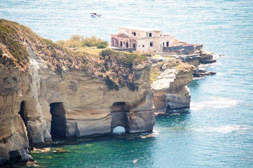 Uncino di roccia sulla costa con edificio abbandonato e mare azzurro sotto, sito storico sulla scogliera con paesaggi marini, immagine di scogliere e natura selvaggia, perfetta per articoli su viaggi e turismo.